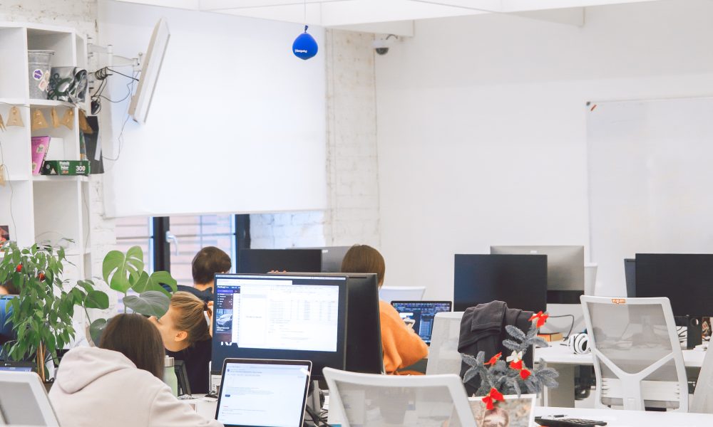People Sitting on White Chairs in Front of Computer Monitor