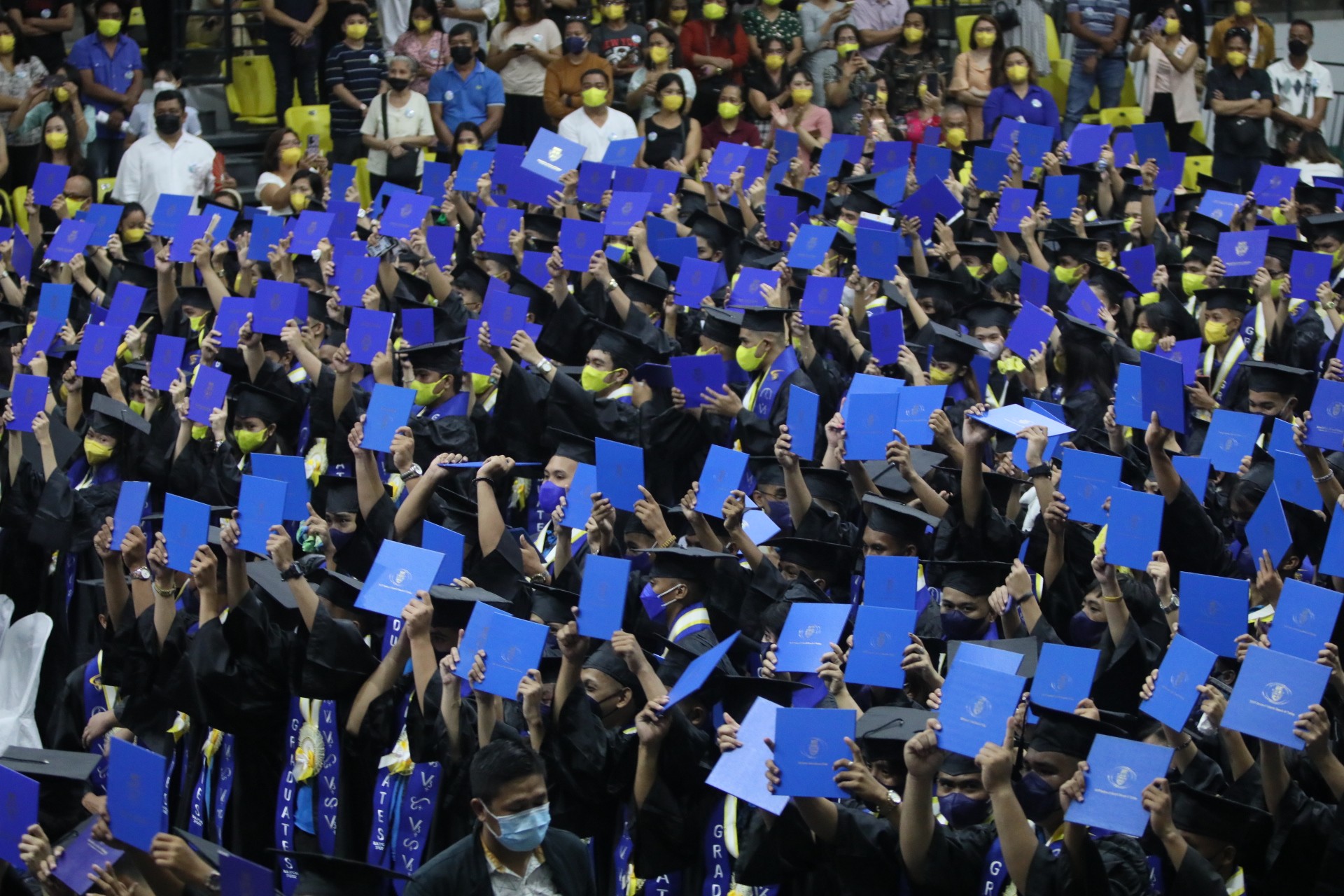 Senior high school graduates raise their diplomas