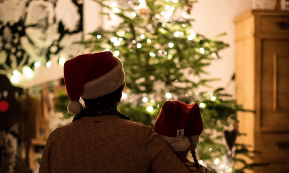 Woman and a girl sitting in front of a Christmas tree