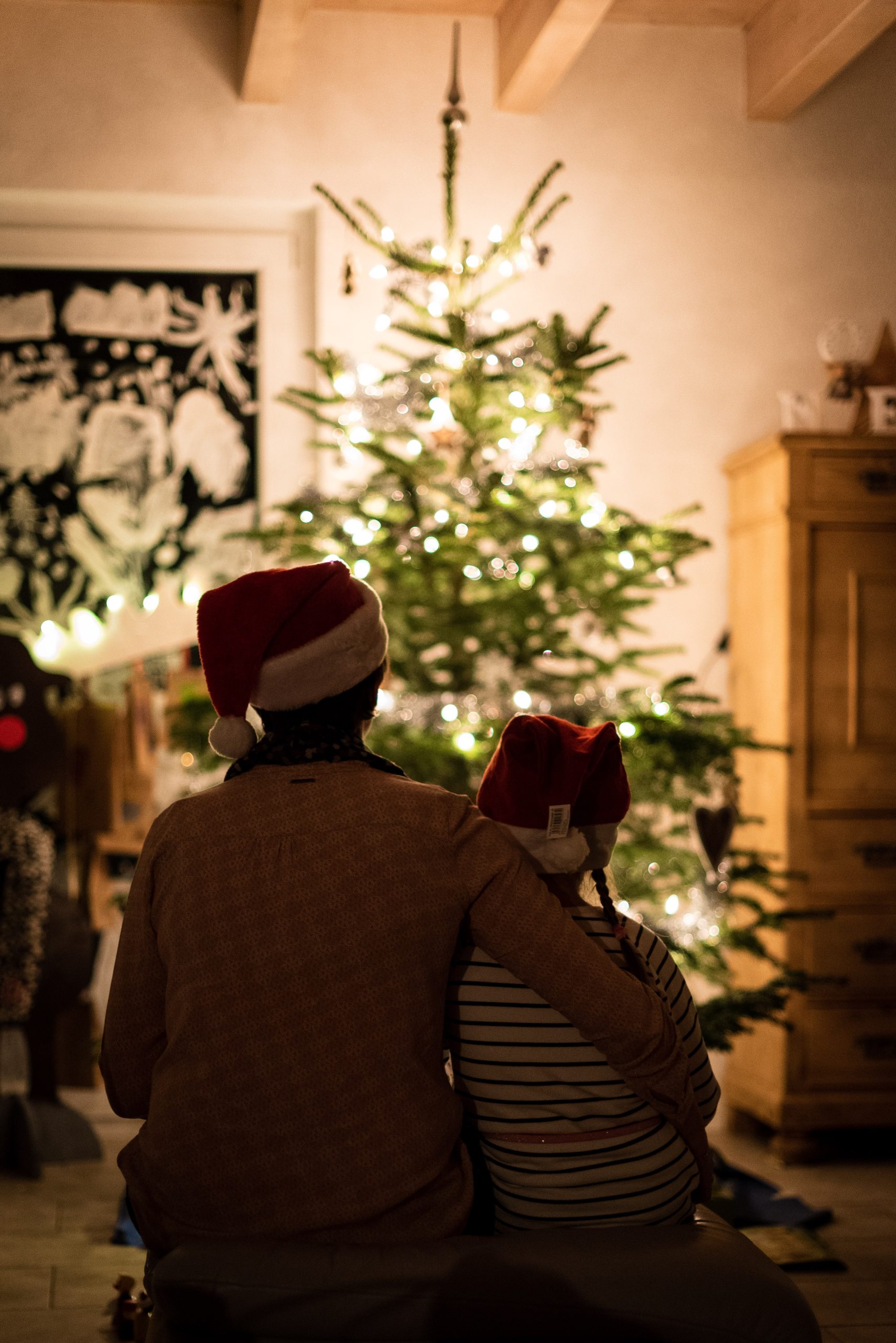 Woman and a girl sitting in front of a Christmas tree