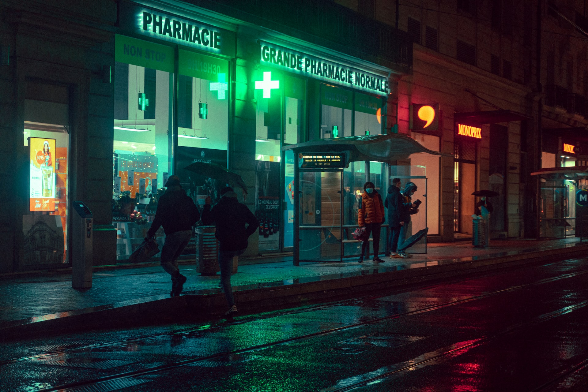 people walking on sidewalks in front of a pharmacy