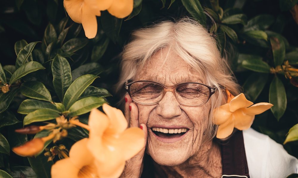 old woman laughing with flowers around