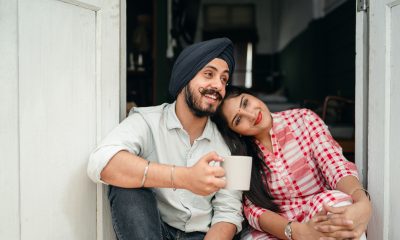 Positive married couple relaxing on threshold of house