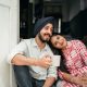 Positive married couple relaxing on threshold of house