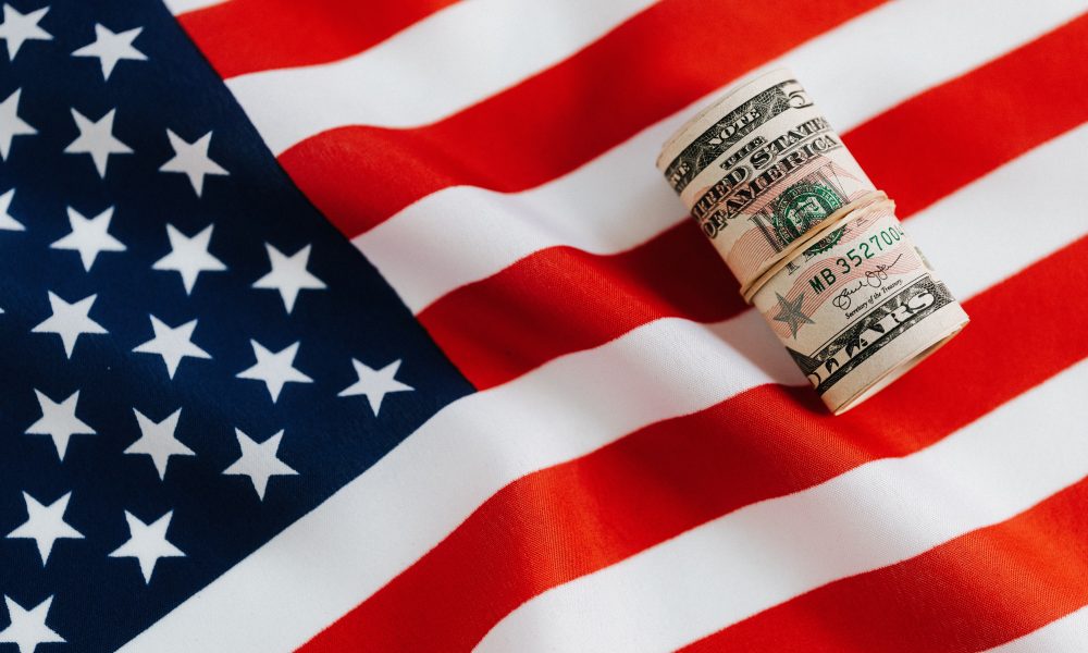 American flag with rolled dollar bills