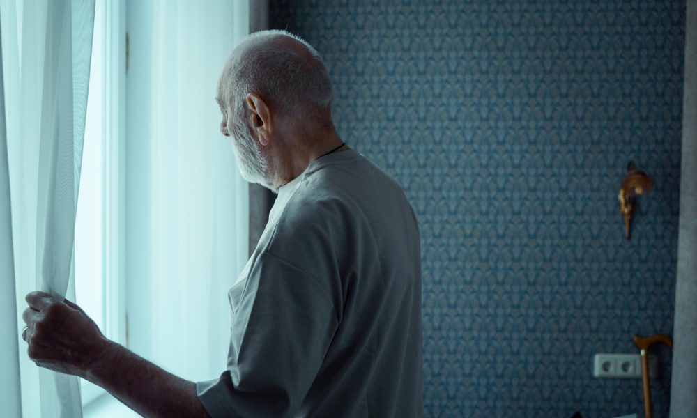 An Elderly Man Opening a Window Curtain