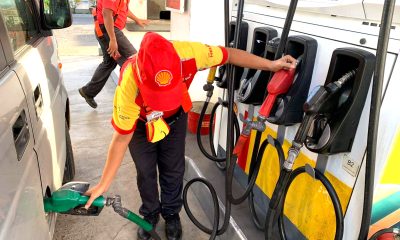 An employee fills up a car's fuel tank at a gasoline station