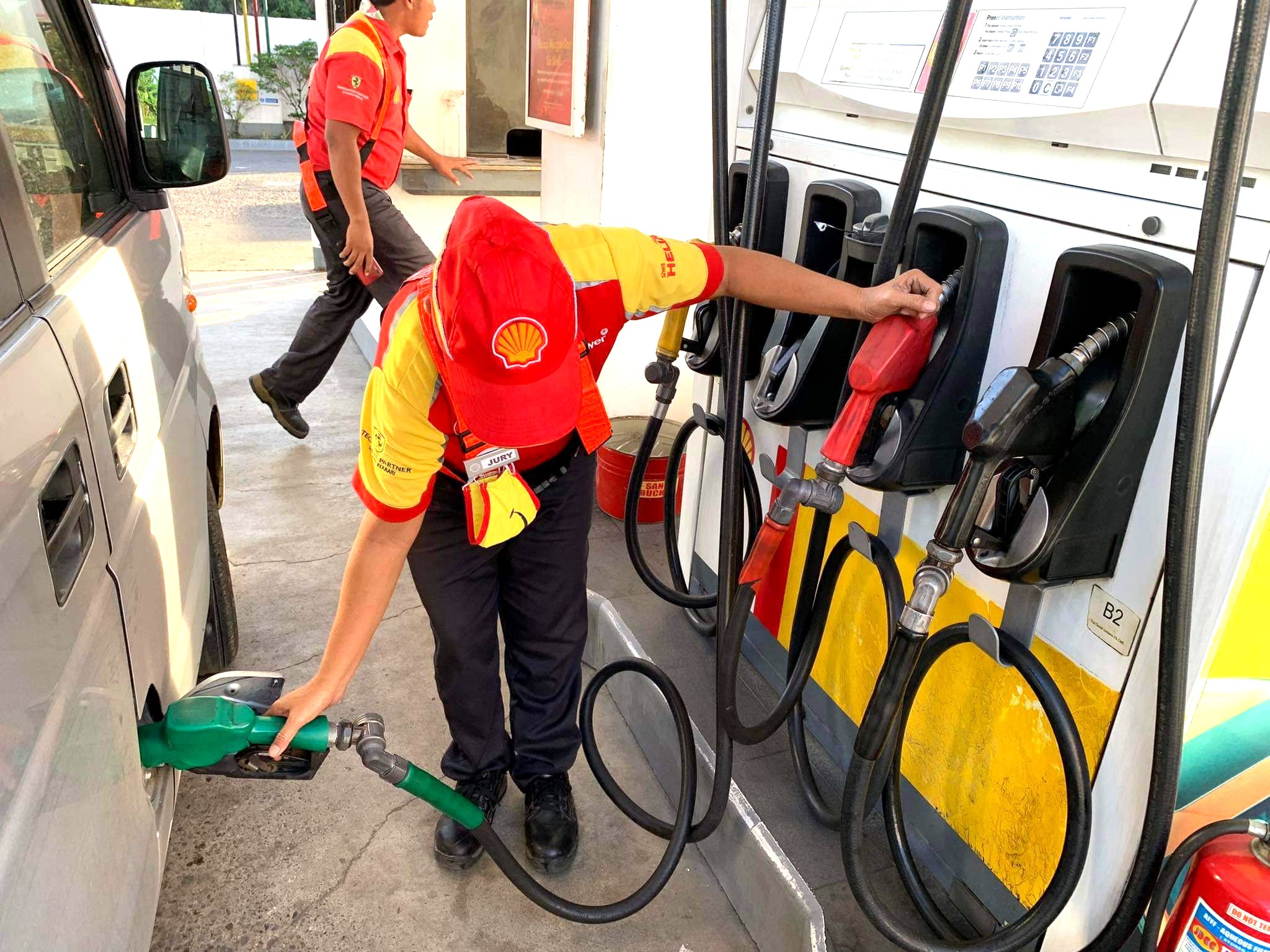 An employee fills up a car's fuel tank at a gasoline station