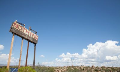 Brown Wooden Signage on Green Grass Field Under Blue Sky and White Clouds