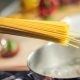 Person Holding Raw Pastas Aiming at Boiling Water in Pot