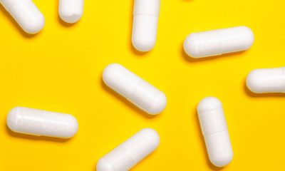 White Medication Capsules on Yellow Surface