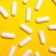 White Medication Capsules on Yellow Surface