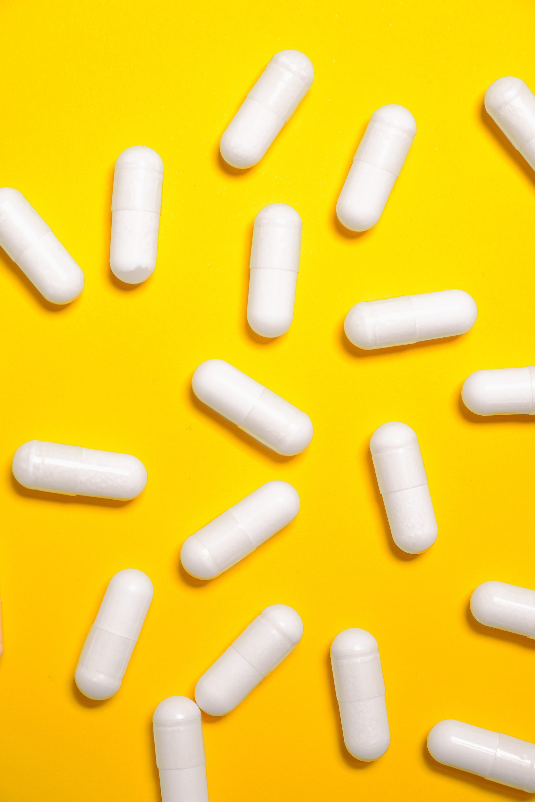 White Medication Capsules on Yellow Surface