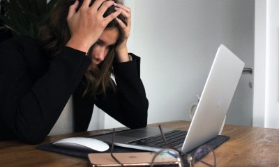 woman holding head in front of laptop