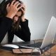 woman holding head in front of laptop