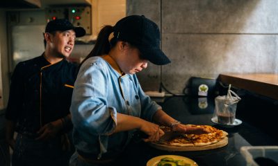 A Woman Cutting a Pizza with a Knife