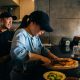 A Woman Cutting a Pizza with a Knife