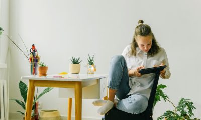 A Woman in White Long Sleeves and Denim Jeans Using Her Tablet