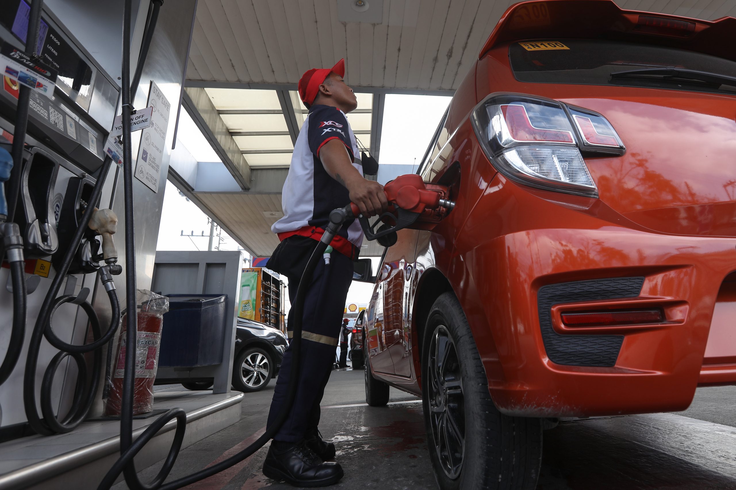 gasoline station employee fills up a vehicle