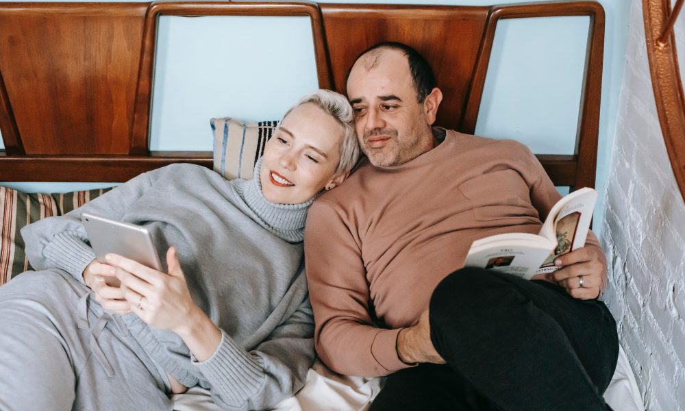 Content multiracial couple watching video on tablet while resting on bed