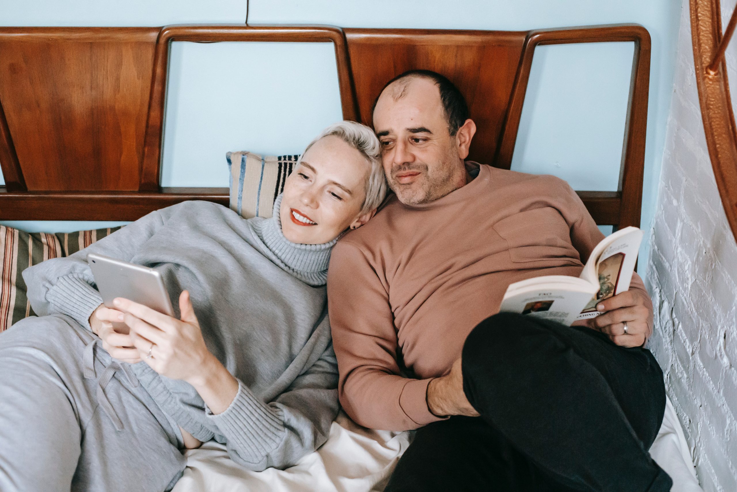 Content multiracial couple watching video on tablet while resting on bed