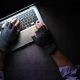 hands with gloves typing on keyboard