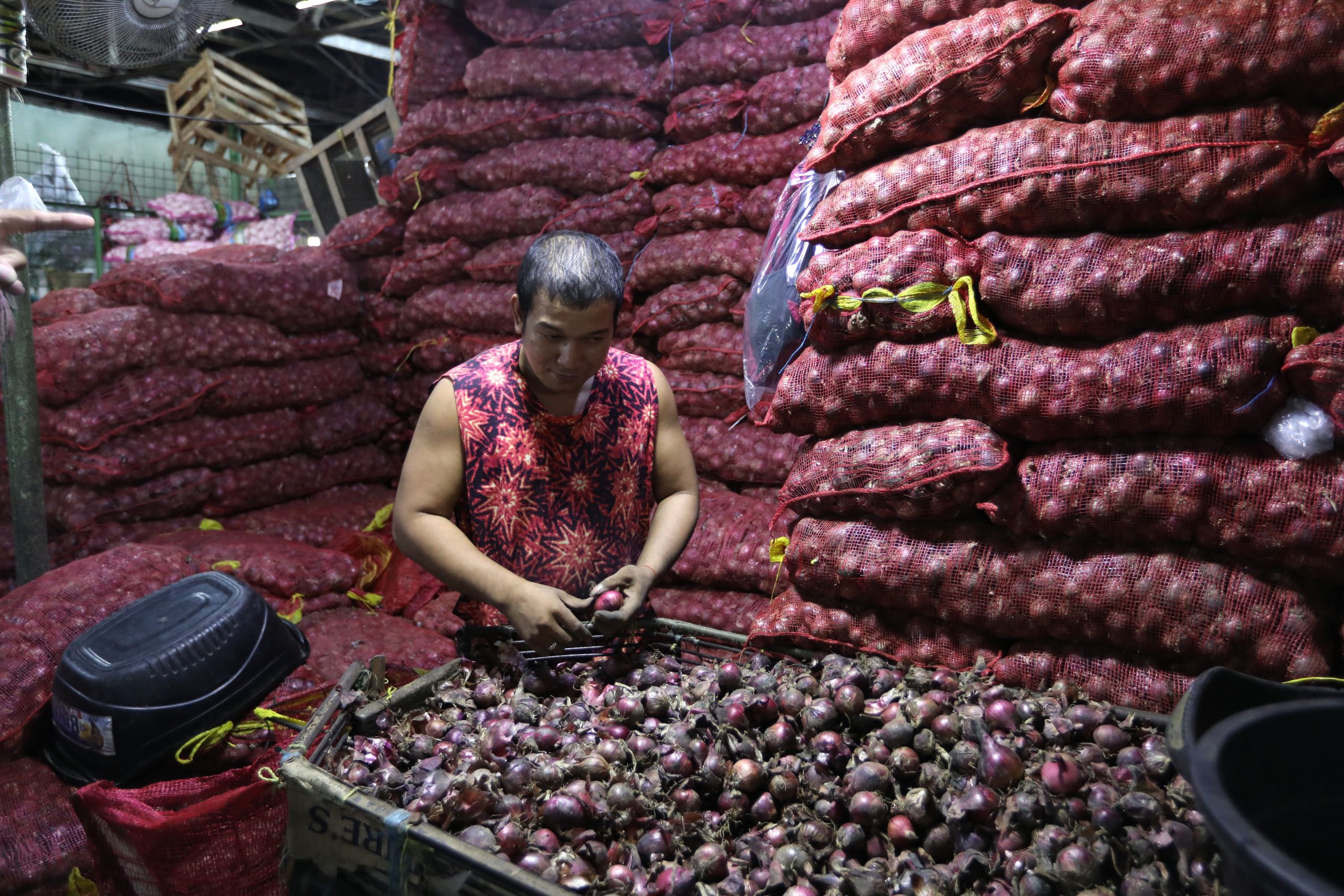 vendor removes the excess skin of red onions