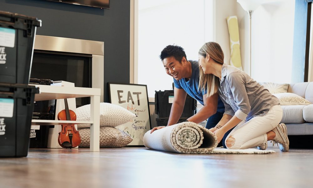 couple rolling out carpet on floor