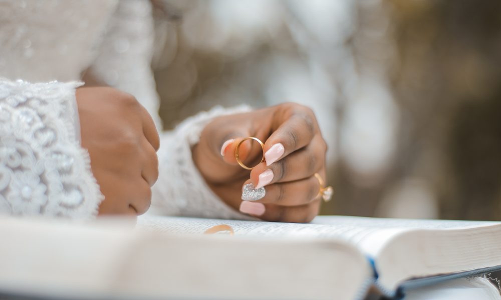 Crop bride holding ring and reading wedding vow