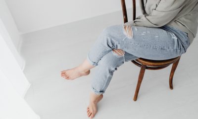 Person Wearing Ripped Jeans Sitting on a Wooden Chair