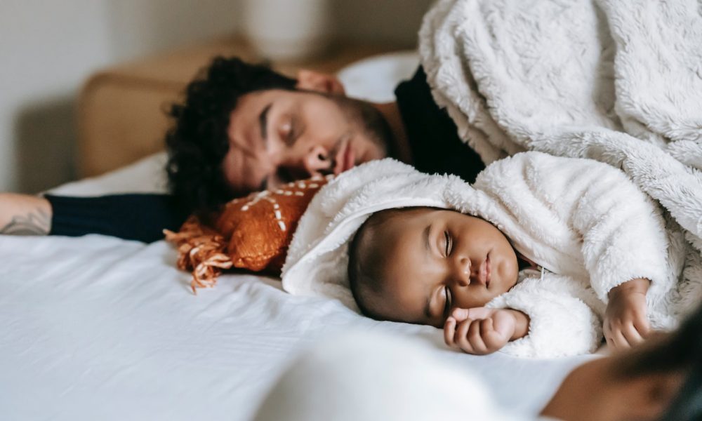 father and son sleeping on bed