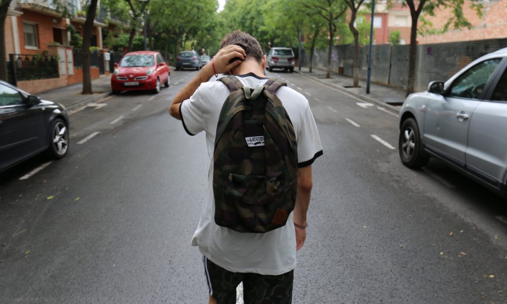 boy scratching his head while walking