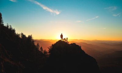 silhouette of man standing on a mountain peak