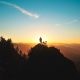 silhouette of man standing on a mountain peak