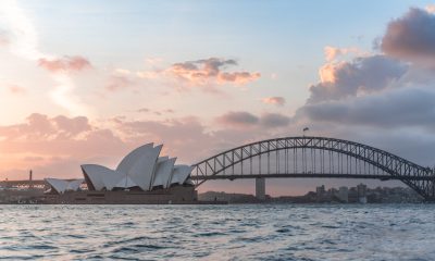 Stylish modern building and arch bridge crossing harbor against cloudy sundown sky