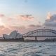 Stylish modern building and arch bridge crossing harbor against cloudy sundown sky