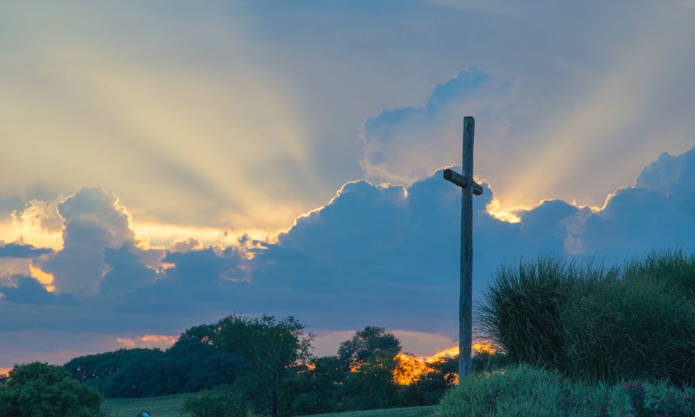 Big Wooden Cross On Green Grass Field Under The White Clouds