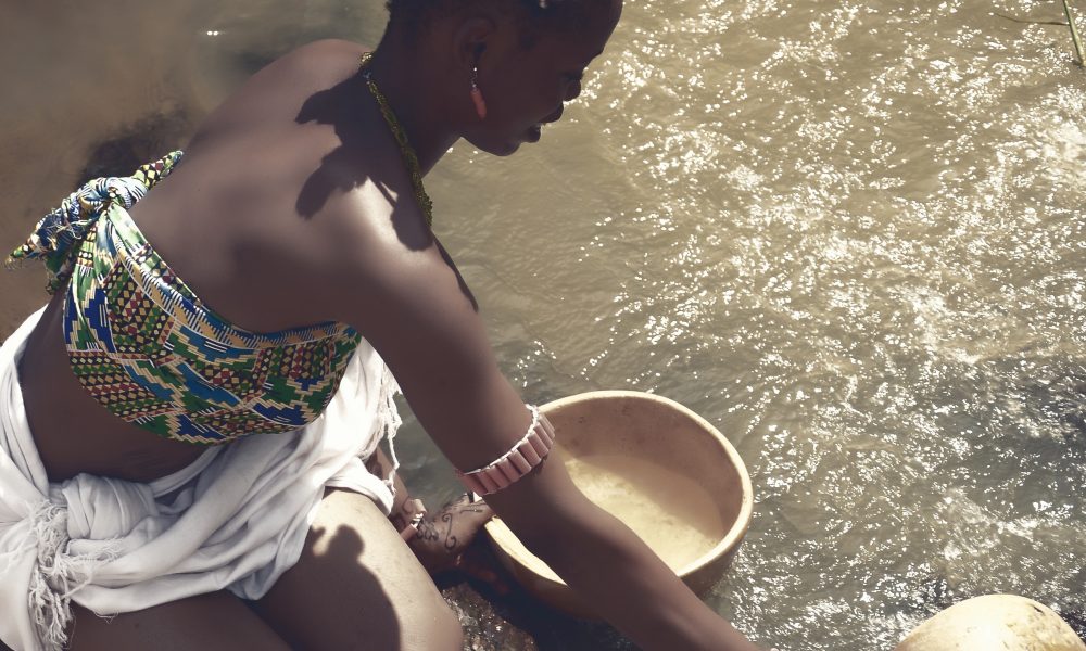Woman Collecting Water From a Water Reservoir into Bowls