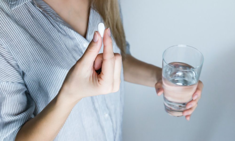 woman holding medicine pill and glass of water