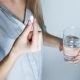 woman holding medicine pill and glass of water