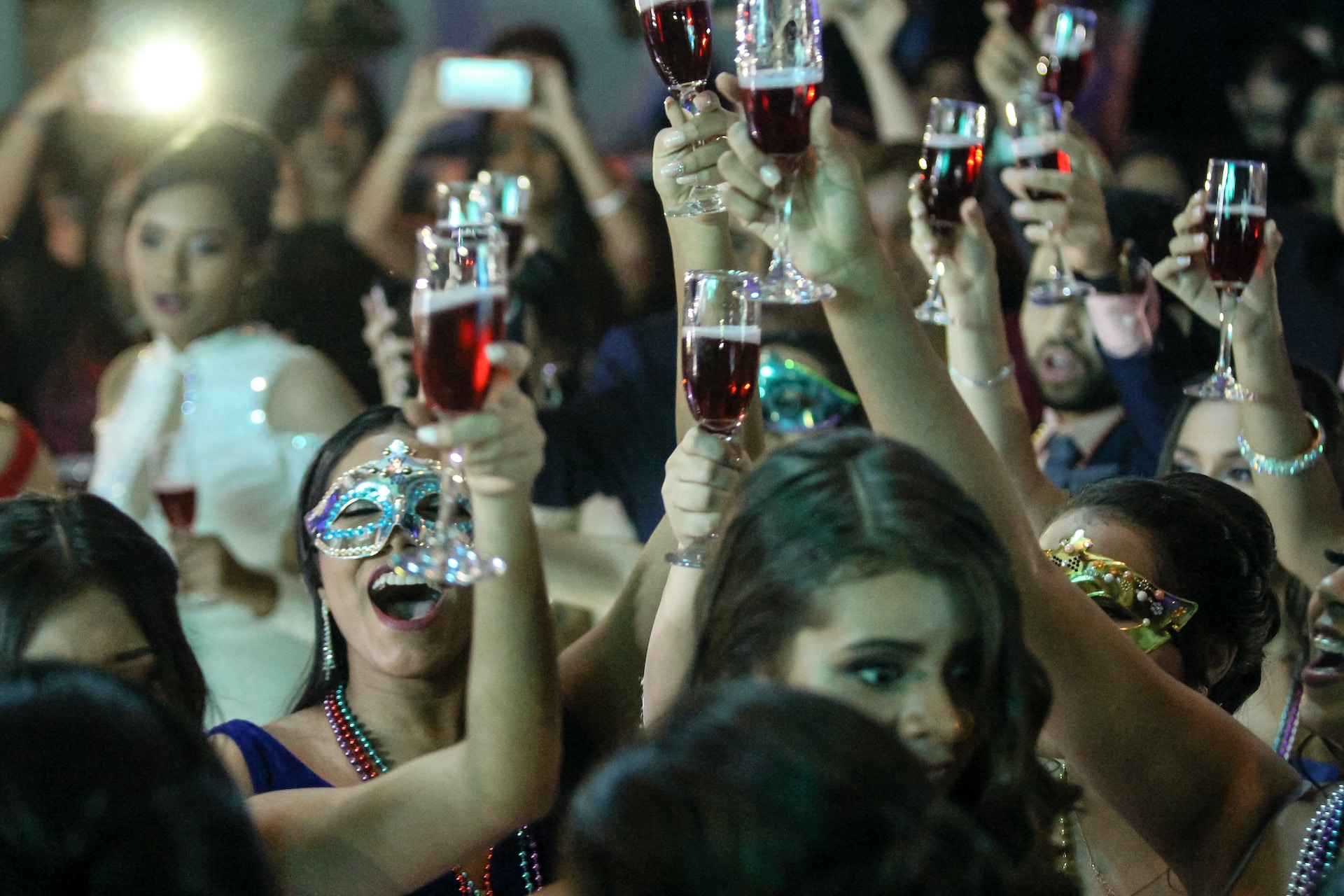 women wearing masks while raising glasses in a party