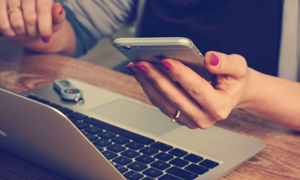 woman holding phone in front of laptop