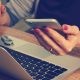 woman holding phone in front of laptop