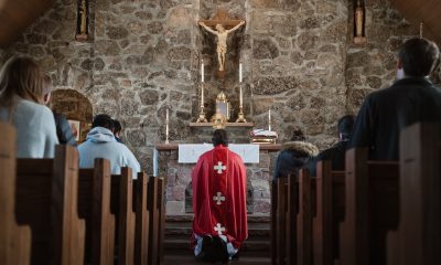 people sitting inside the church while priest kneeling in front of the altar