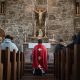 people sitting inside the church while priest kneeling in front of the altar