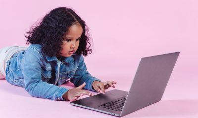 Adorable black girl browsing laptop on floor