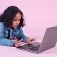 Adorable black girl browsing laptop on floor