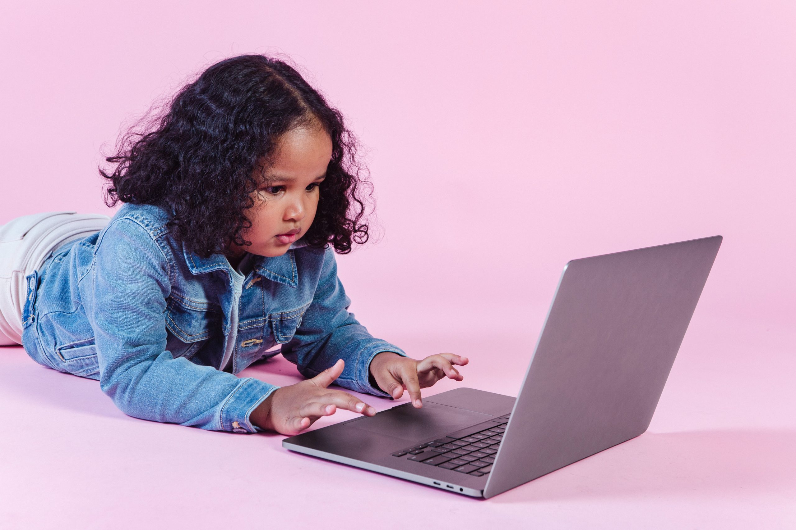 Adorable black girl browsing laptop on floor