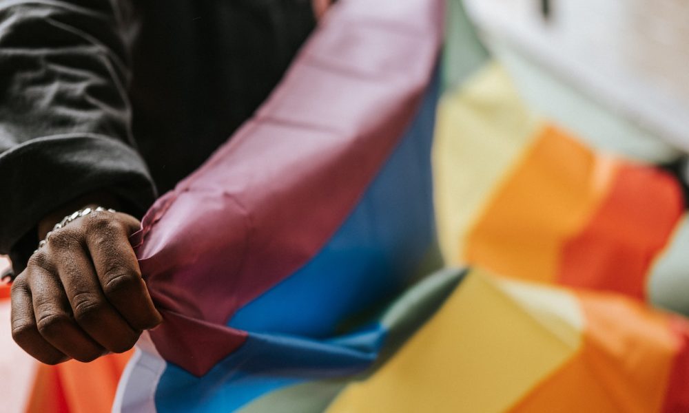 hand holding an lgbtiq+ flag