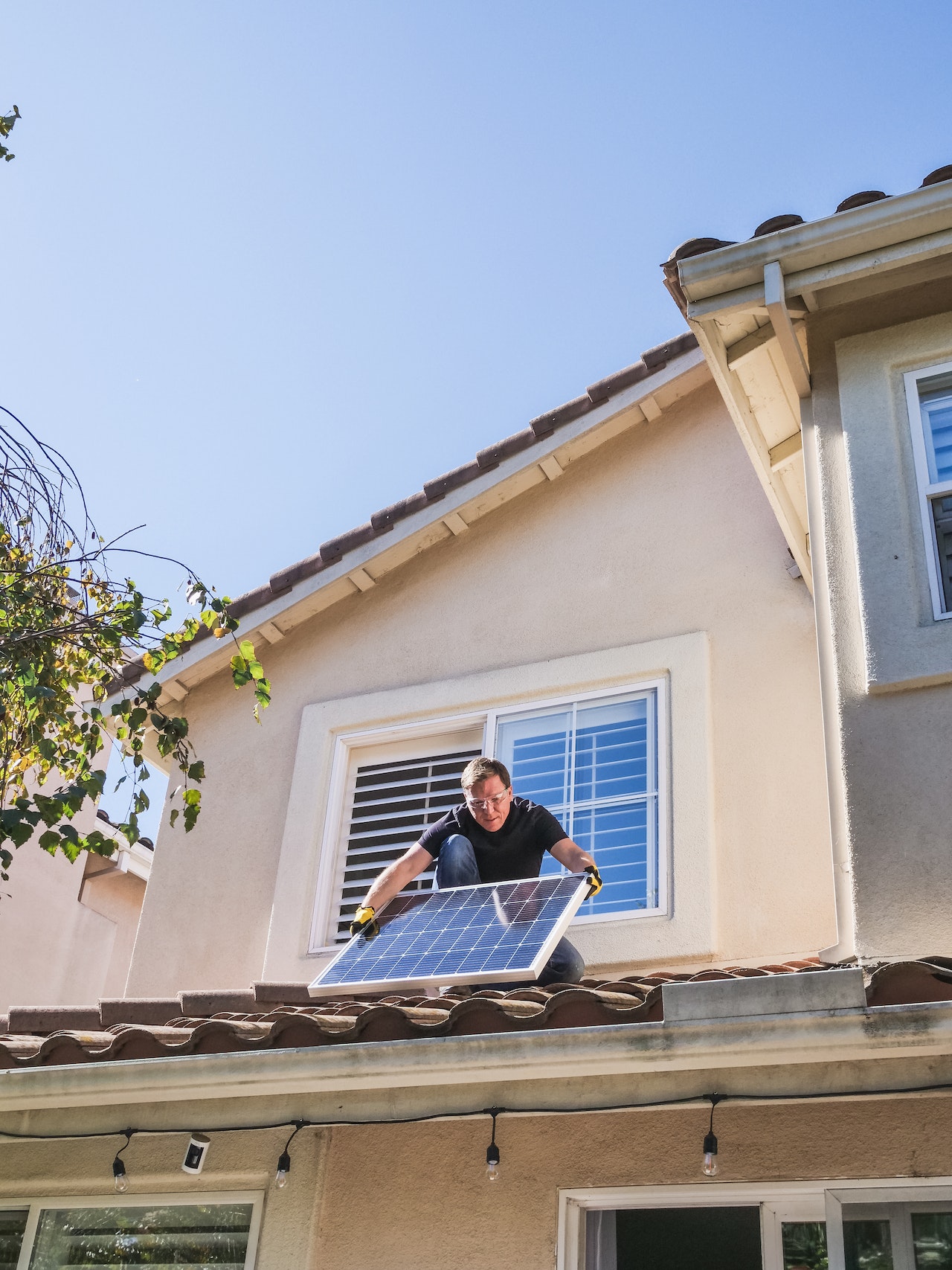 man installing solar panel on roof